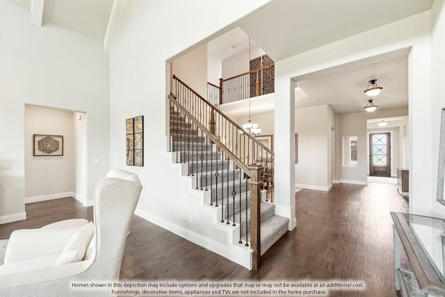 stairs featuring an inviting chandelier, a towering ceiling, and hardwood / wood-style floors