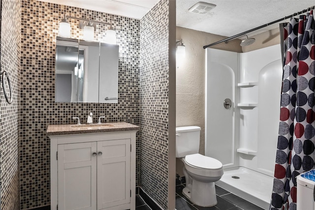 bathroom featuring vanity, a shower with shower curtain, toilet, a textured ceiling, and tile walls