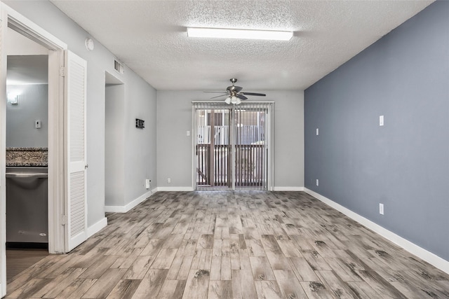 empty room with ceiling fan, a textured ceiling, and light hardwood / wood-style flooring