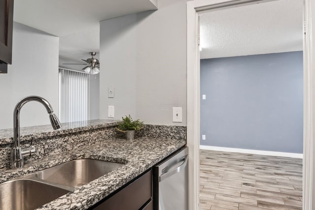 kitchen featuring dishwasher, sink, dark stone counters, a textured ceiling, and light wood-type flooring