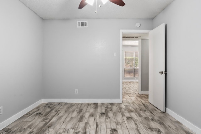 unfurnished room with a textured ceiling, light hardwood / wood-style floors, and ceiling fan