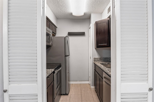 kitchen featuring dark brown cabinetry, stainless steel appliances, and stone countertops