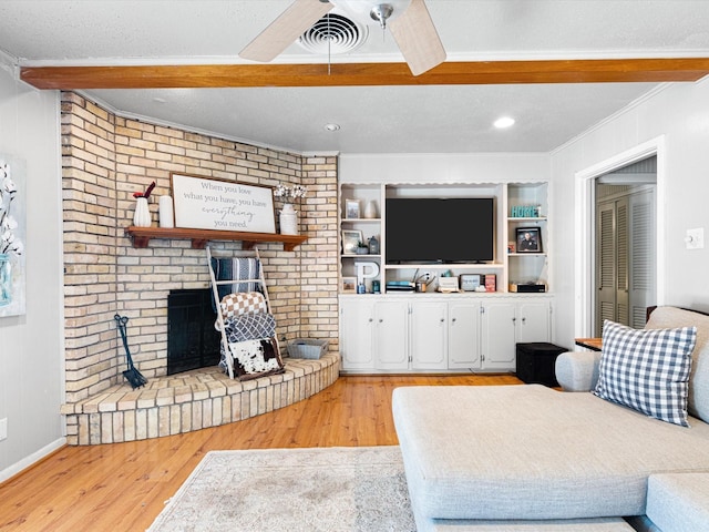 living room featuring ceiling fan, light wood-type flooring, a fireplace, and ornamental molding