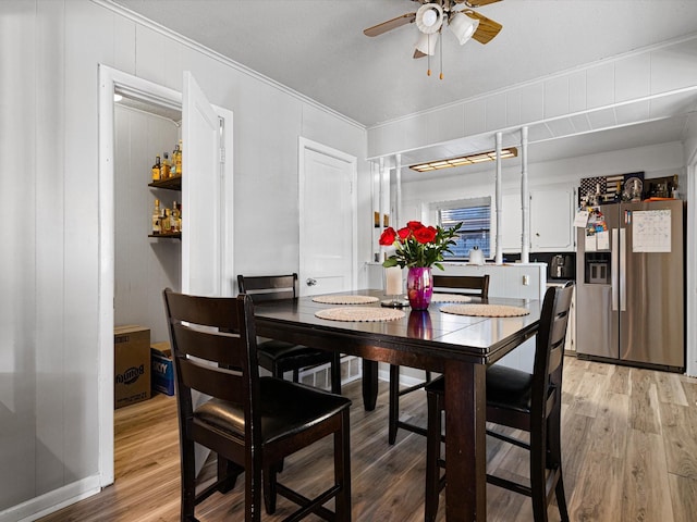 dining space with crown molding, ceiling fan, and light wood-type flooring