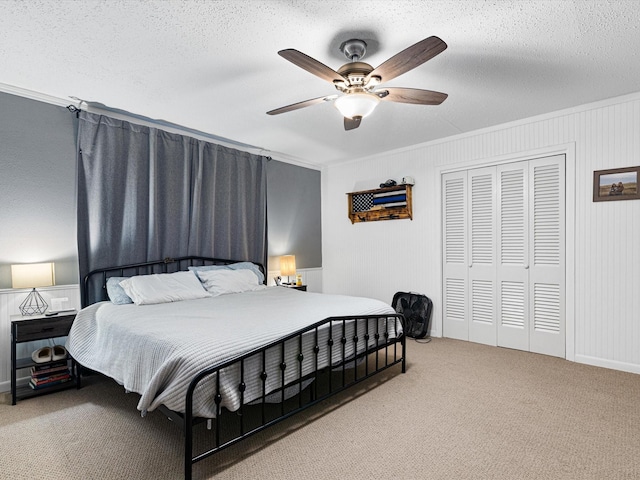 carpeted bedroom with ceiling fan, a closet, crown molding, and a textured ceiling