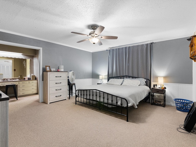 carpeted bedroom with ceiling fan, a textured ceiling, and ornamental molding