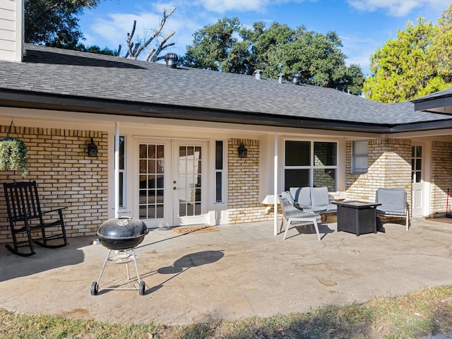 rear view of property featuring french doors, a patio, and an outdoor living space with a fire pit