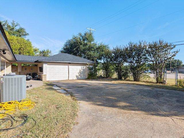 view of side of home featuring central AC unit, a garage, and a lawn