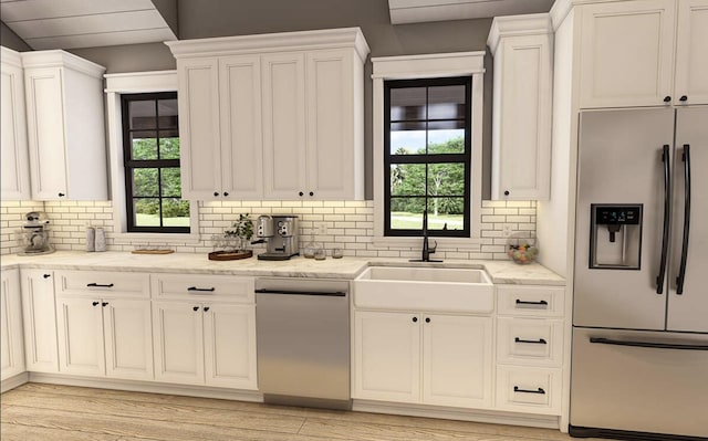 kitchen featuring light stone countertops, backsplash, stainless steel appliances, sink, and white cabinets