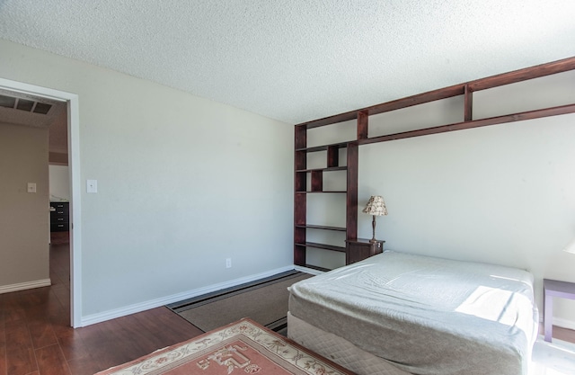 bedroom with a textured ceiling and dark hardwood / wood-style floors