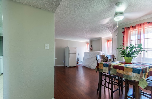 dining room featuring crown molding, dark wood-type flooring, and a textured ceiling