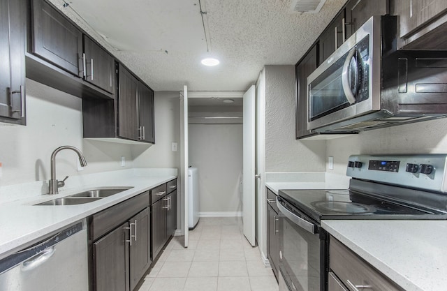 kitchen featuring a textured ceiling, sink, light tile patterned floors, and stainless steel appliances