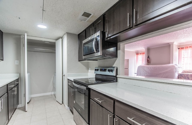 kitchen featuring dark brown cabinetry, a wealth of natural light, stainless steel appliances, and a textured ceiling