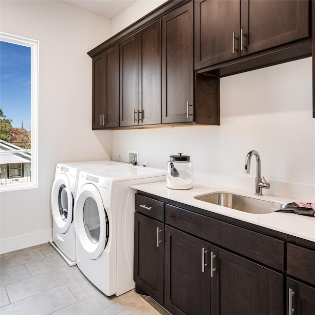 laundry area with sink, light tile patterned floors, cabinets, and independent washer and dryer