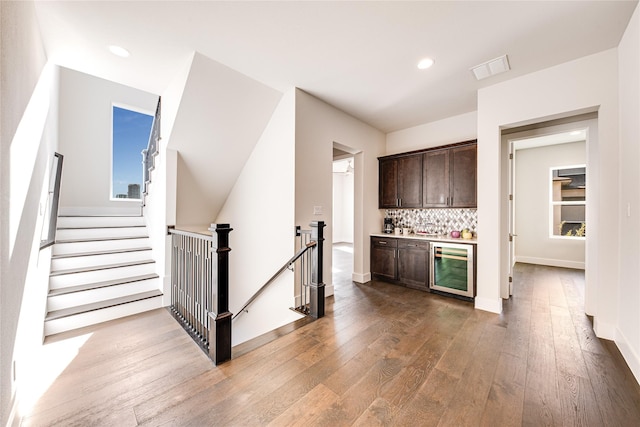 kitchen with tasteful backsplash, dark brown cabinets, hardwood / wood-style floors, and beverage cooler