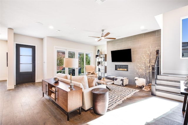 living room with a tile fireplace, ceiling fan, and dark hardwood / wood-style floors