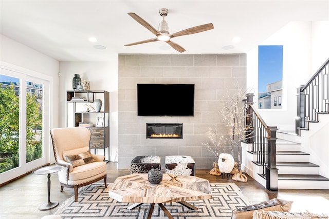 living room featuring a tiled fireplace, ceiling fan, hardwood / wood-style floors, and a healthy amount of sunlight