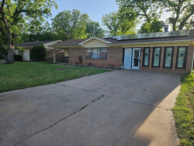 single story home with solar panels and a front lawn