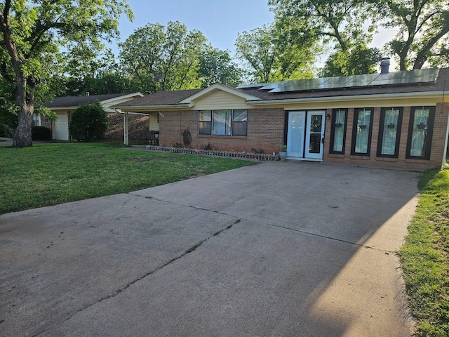 ranch-style home with a front lawn and solar panels