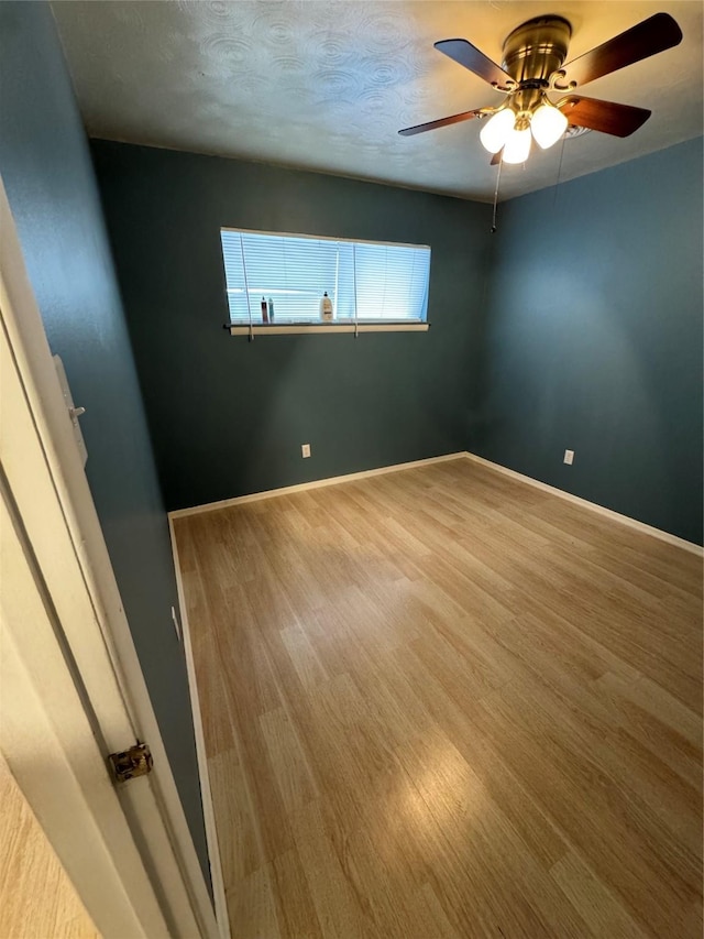 empty room featuring ceiling fan, wood-type flooring, and a textured ceiling