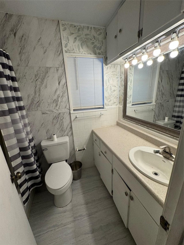 bathroom featuring vanity, toilet, a shower with shower curtain, and tile walls