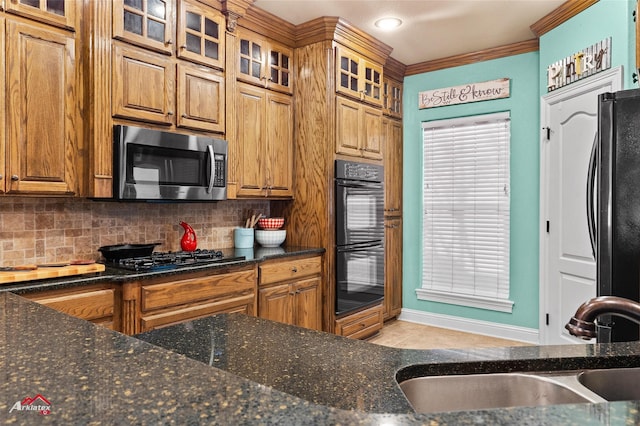 kitchen with decorative backsplash, ornamental molding, sink, black appliances, and dark stone countertops