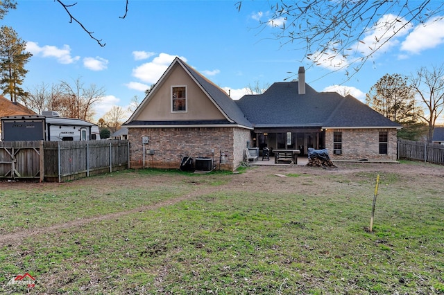 rear view of property with a lawn, cooling unit, and a patio