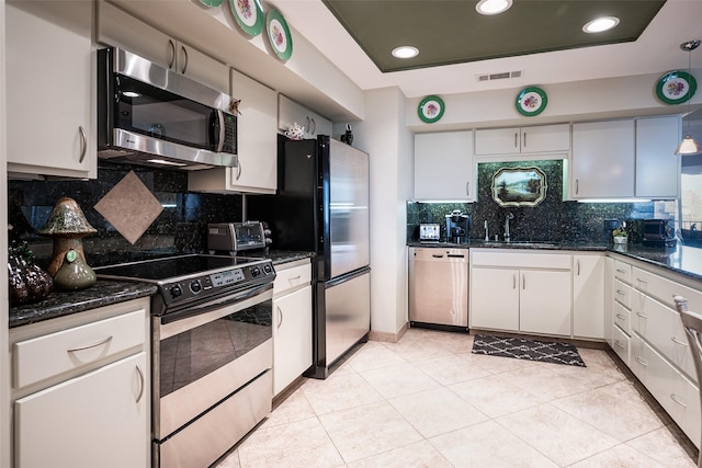 kitchen featuring sink, decorative backsplash, light tile patterned floors, appliances with stainless steel finishes, and white cabinetry