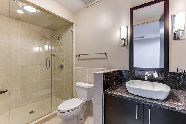 bathroom with vanity, tile patterned flooring, toilet, tile walls, and walk in shower