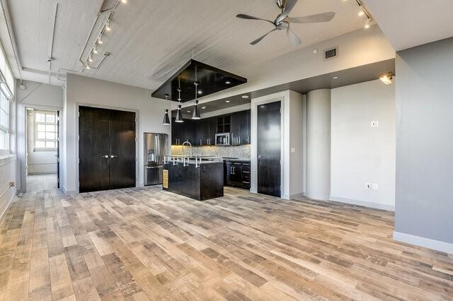 kitchen featuring pendant lighting, a kitchen island with sink, ceiling fan, light hardwood / wood-style floors, and stainless steel appliances