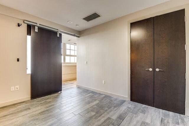 unfurnished bedroom featuring a barn door, a closet, and light hardwood / wood-style flooring