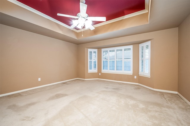 spare room with carpet floors, a raised ceiling, ornamental molding, and baseboards