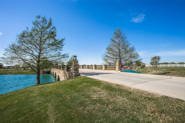 view of yard featuring a water view, driveway, and fence