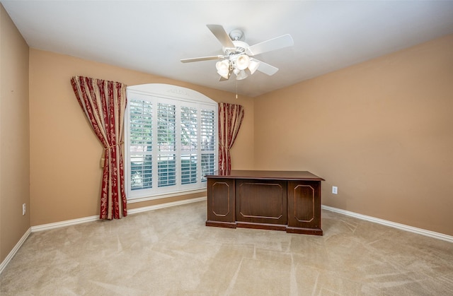 unfurnished office with light carpet, ceiling fan, and baseboards