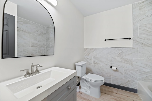 bathroom with vanity, toilet, and tile walls