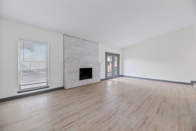 unfurnished living room featuring a high end fireplace and light hardwood / wood-style flooring