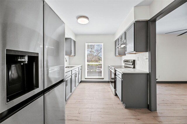 kitchen featuring gray cabinetry, tasteful backsplash, appliances with stainless steel finishes, and light hardwood / wood-style flooring