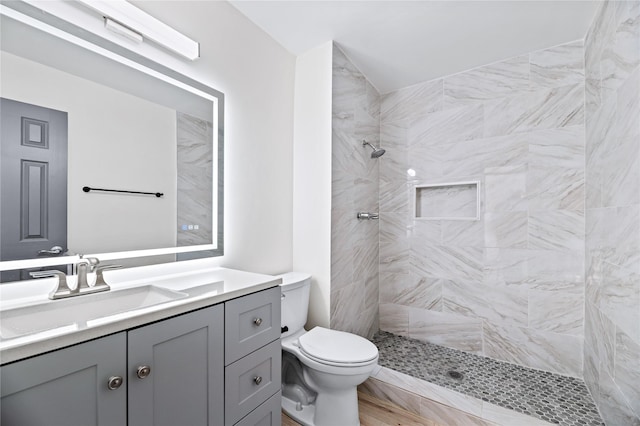 bathroom with tiled shower, vanity, and toilet