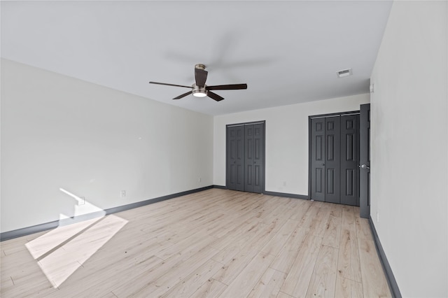 unfurnished bedroom with multiple closets, ceiling fan, and light hardwood / wood-style flooring