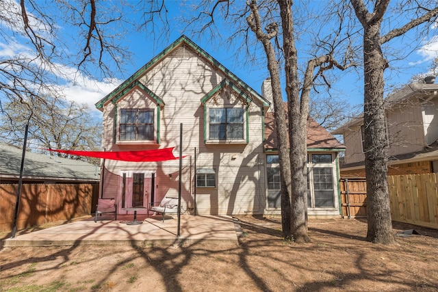 back of property featuring fence, a patio area, and a chimney
