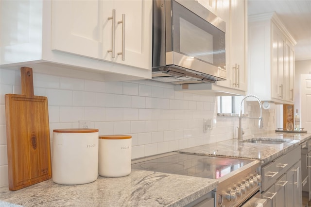 6010 Paradise Dr, Arlington, TX 76001 - kitchen with stainless steel appliances, white cabinetry, tasteful backsplash, and light stone counters
