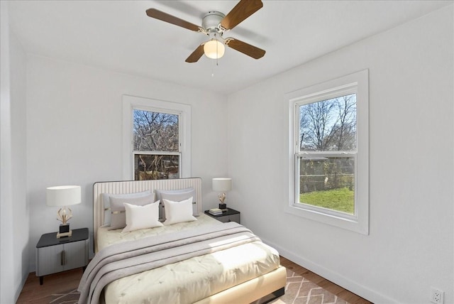 bedroom with multiple windows, hardwood / wood-style flooring, and ceiling fan