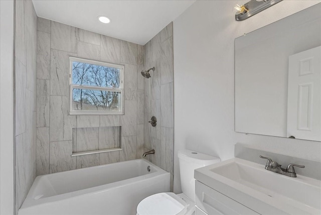 full bathroom featuring tiled shower / bath, vanity, and toilet