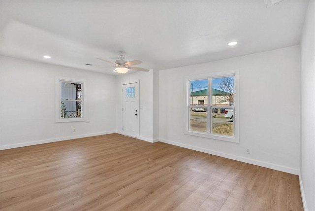 empty room with ceiling fan and light hardwood / wood-style flooring