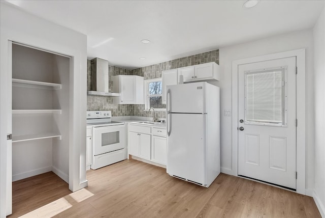 kitchen featuring wall chimney range hood, white appliances, light hardwood / wood-style flooring, sink, and white cabinetry