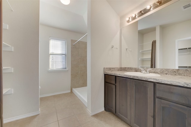 bathroom with a tile shower, vanity, and tile patterned floors