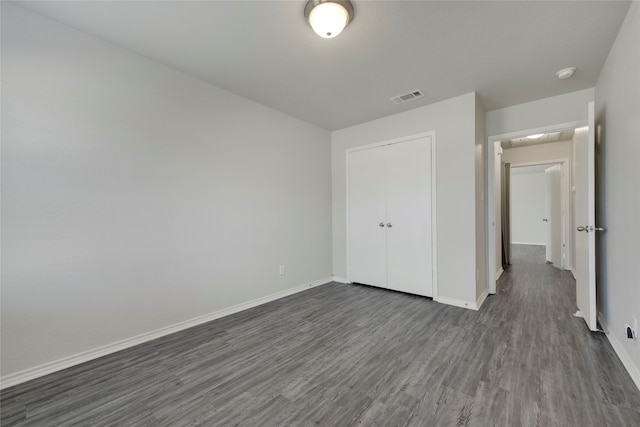 unfurnished bedroom featuring a closet and dark hardwood / wood-style floors