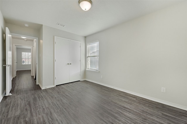 unfurnished bedroom with dark hardwood / wood-style floors and a closet