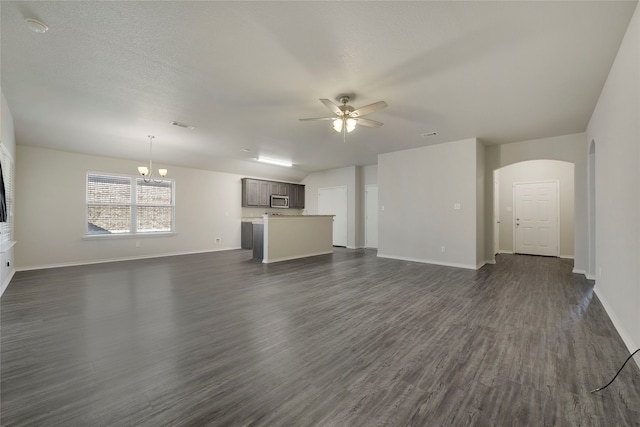 unfurnished living room with dark wood-type flooring and ceiling fan with notable chandelier