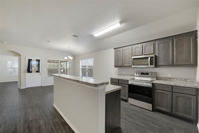 kitchen featuring lofted ceiling, dark brown cabinets, dark hardwood / wood-style flooring, pendant lighting, and stainless steel appliances